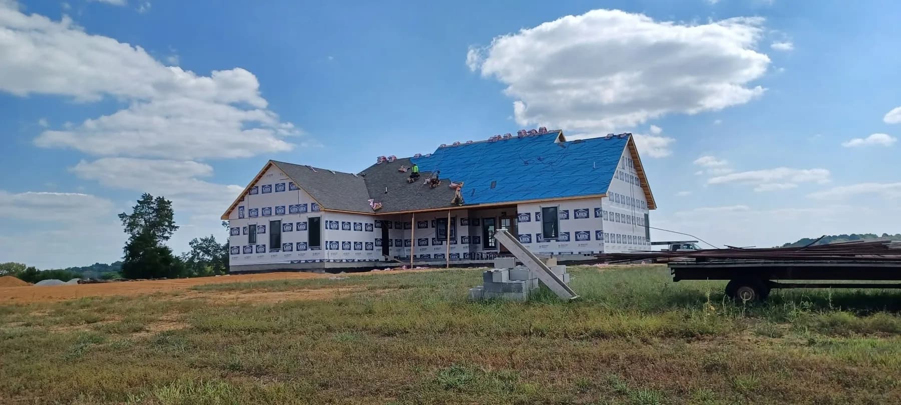 New-construction home with blue metal roof in progress