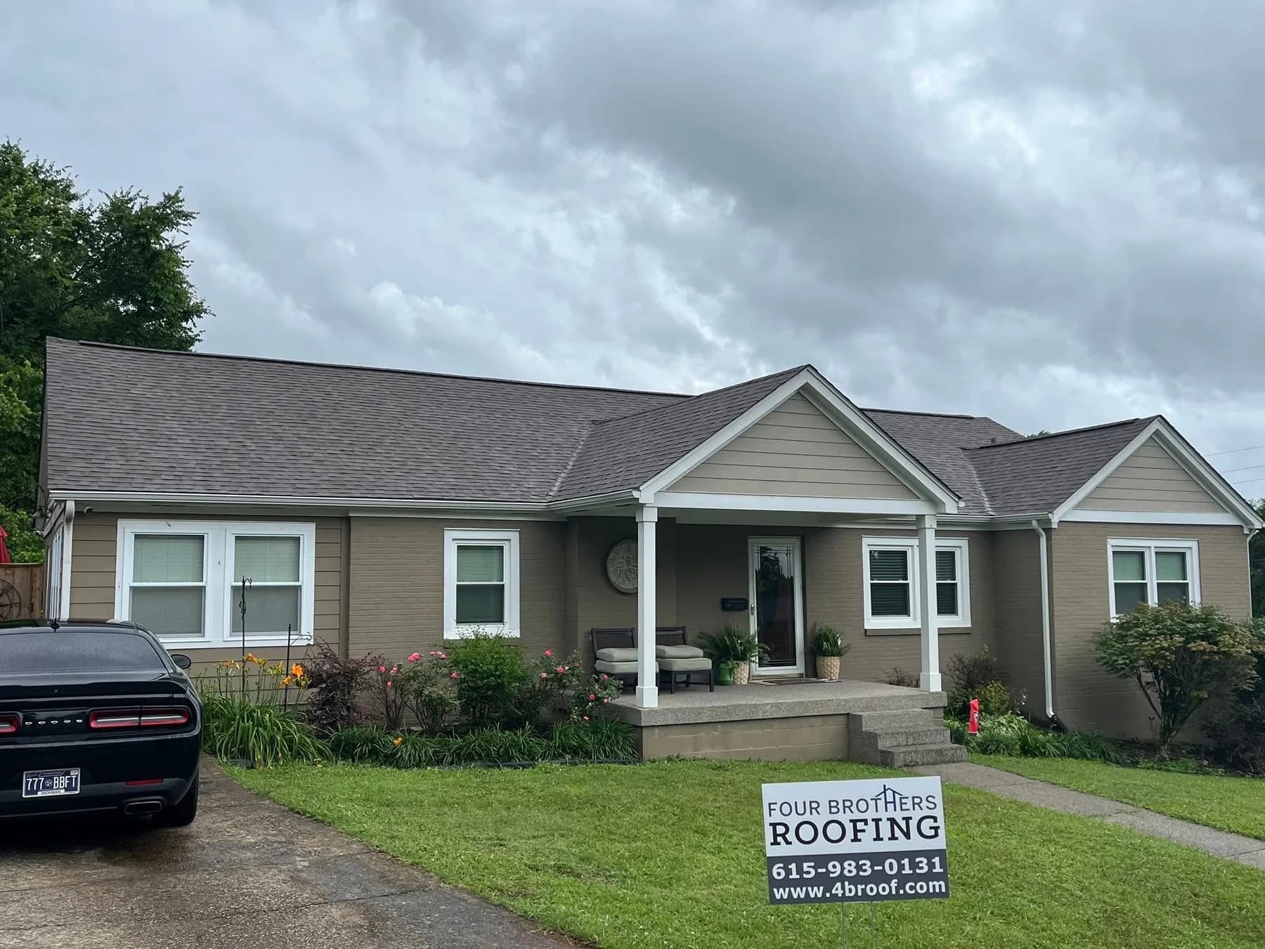 Completed Four Brothers Roofing residential roof with yard sign