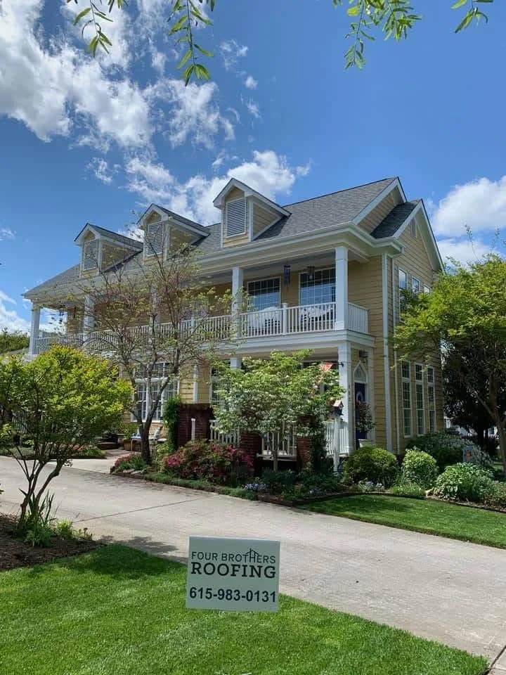 Two-story residential roof project with yard sign